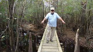 Tim pointing out two cypress knees, one on each side of the bridge
